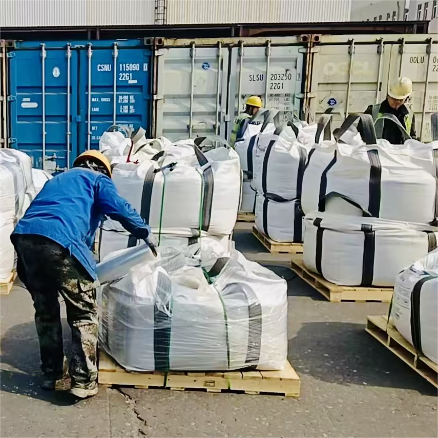 Workers handling jumbo bag packaging for garnet abrasive